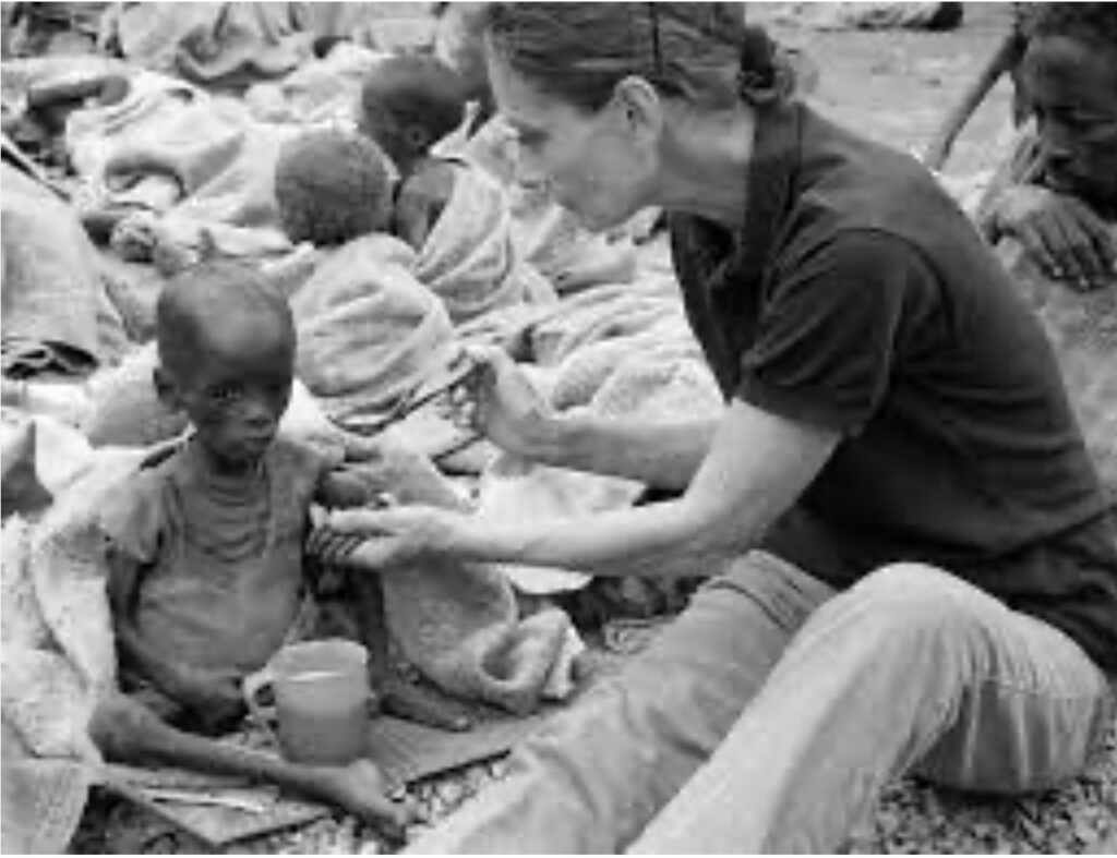 mulheres incríveis - Audrey Hepburn, a embaixadora do Amor, alimentando criança magérrima cercada por outras crianças em condições de pobreza absoluta